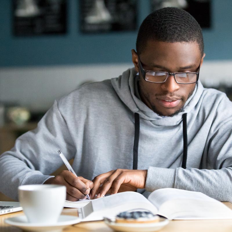 An image of a student taking notes from a book