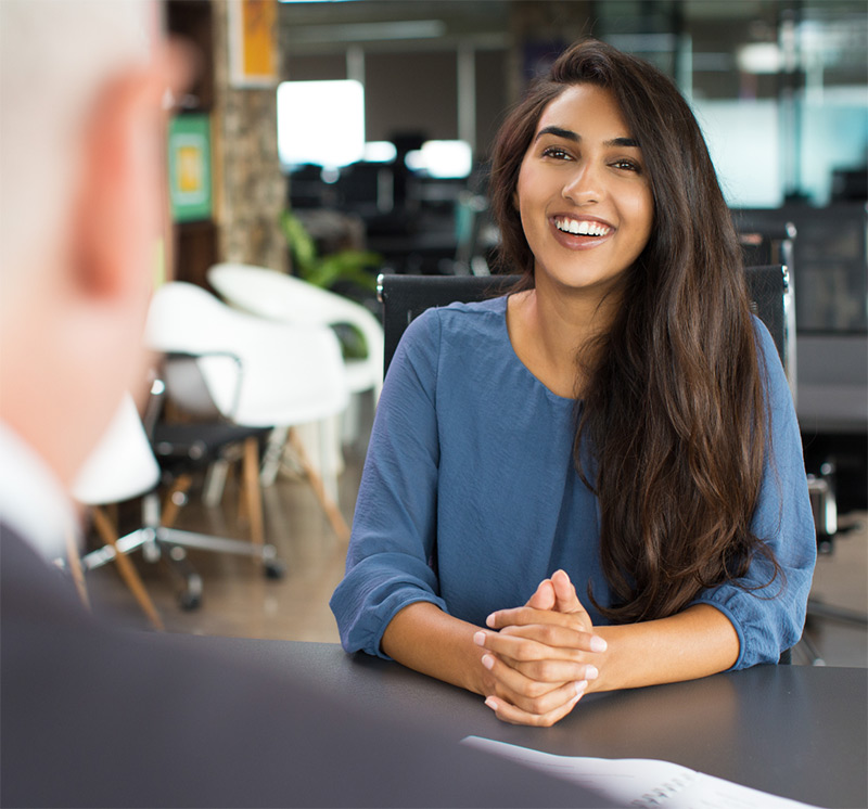 A man and a woman talking at a desk, illustrating process